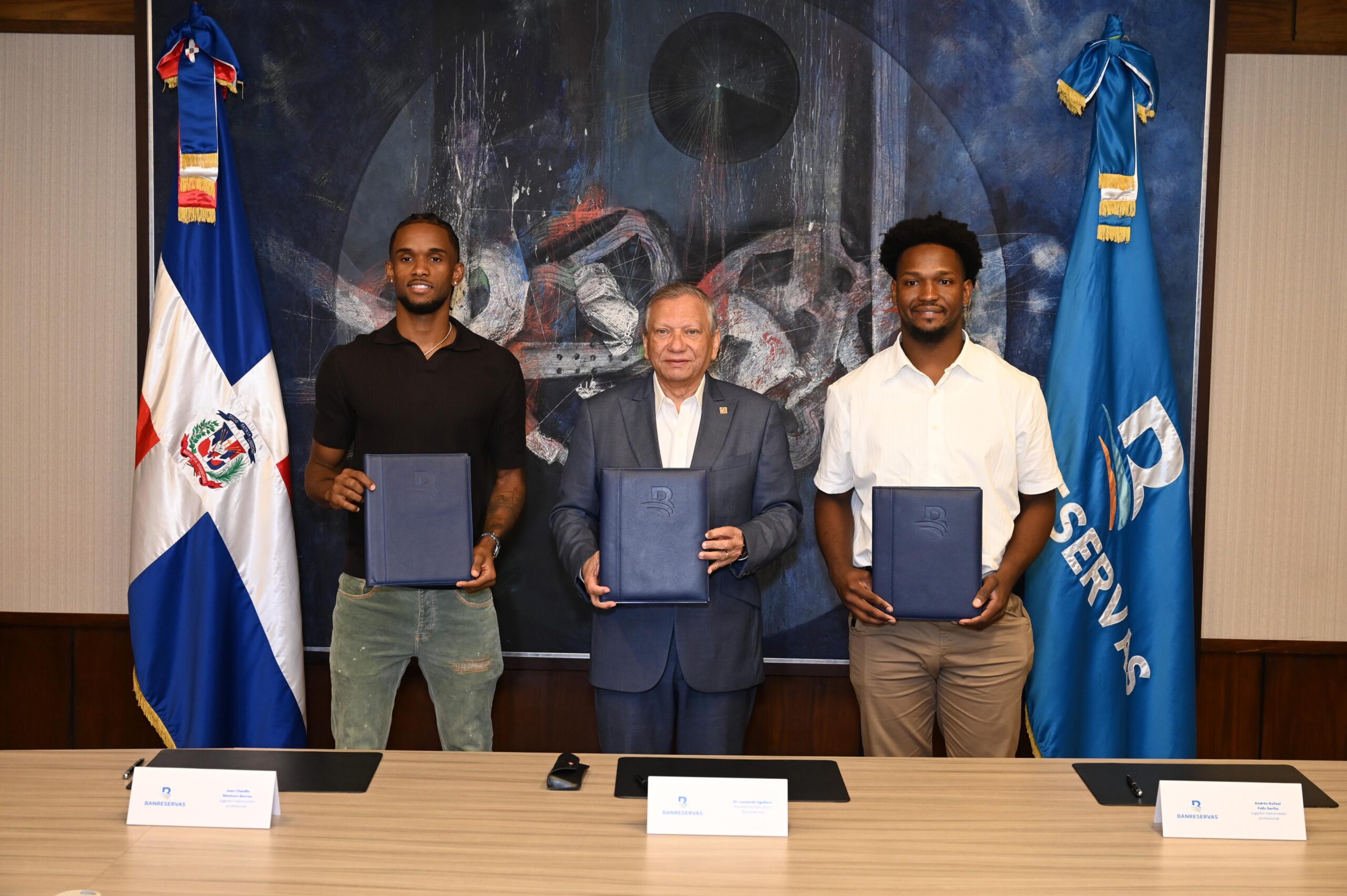 El presidente ejecutivo de Banreservas, doctor Leonardo Aguilera, firma un acuerdo de colaboración con los baloncestistas Jean Montero y Andrés Feliz, quienes desde ya son embajadores de la marca ante el mundo.